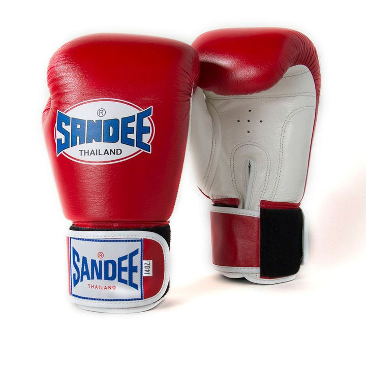 A pair of red and white Velcro boxing gloves with the brand name 'Sandee' displayed on the wrist strap.